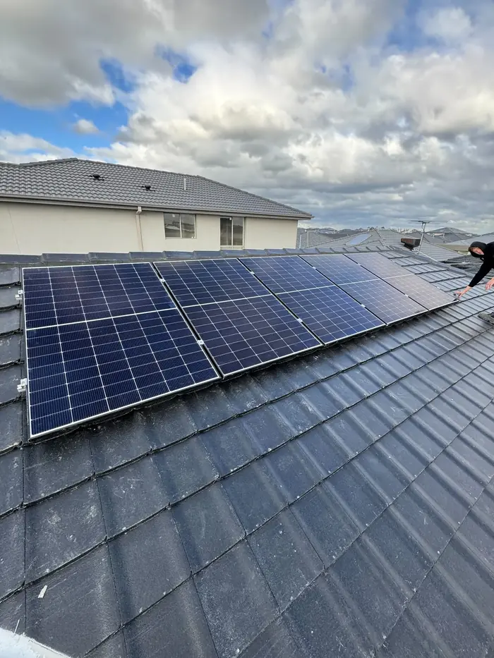Solar panels on a dark concrete tile roof under a cloudy sky